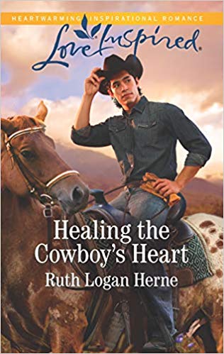 A cowboy in a black hat and denim shirt on a brown horse in front of the mountains - Love Inspired July 2019 - Healing the Cowboy's Heart by Ruth Logan Herne